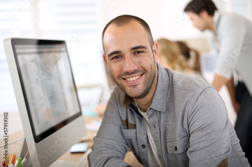 Cheerful guy sitting in front of desktop computer