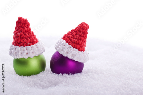 green and pink christmas ball decoration with santa hat in snow