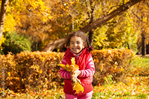 Nice little girl with bunch of yellow leaves