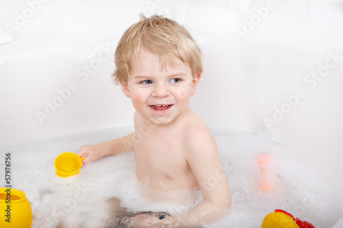 Adorable toddler boy having fun in bathtub