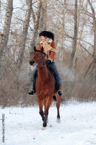 Pretty women goes on the bay horse in winter road © horsemen