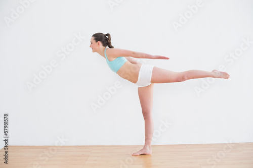 Sporty woman standing on one leg in fitness center