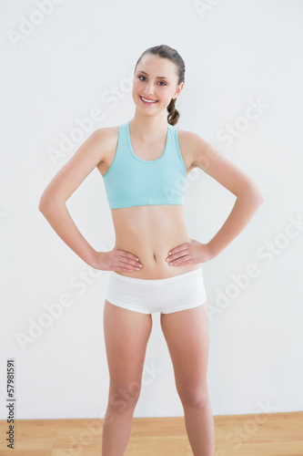 Smiling toned woman standing in fitness studio