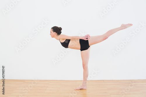 Sporty young woman standing on one leg in fitness center