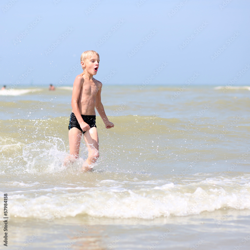 Happy teenager boy plays on the beach