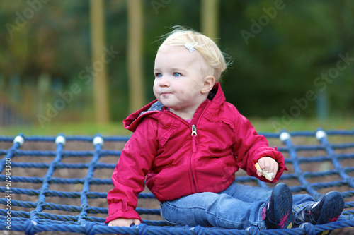 Cute baby girl relaxing on a swing net at playground