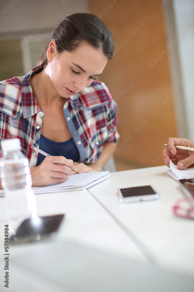 College student writing notes in class College student writing notes in class