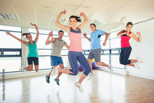 Fitness class and instructor jumping in fitness studio
