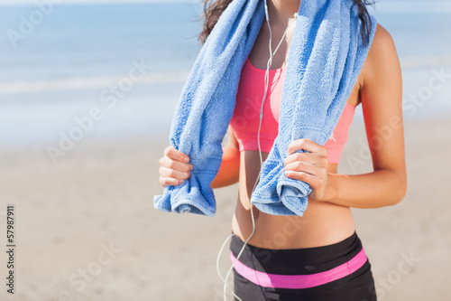 Mid section of healthy woman with towel around neck on beach
