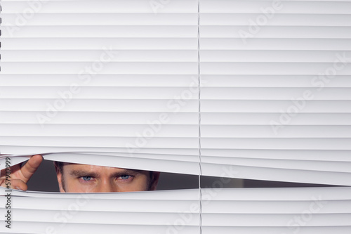 Businessman peeking through blinds
