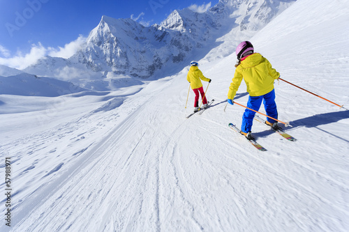 Skiing, skiers on ski run - child skiing downhill