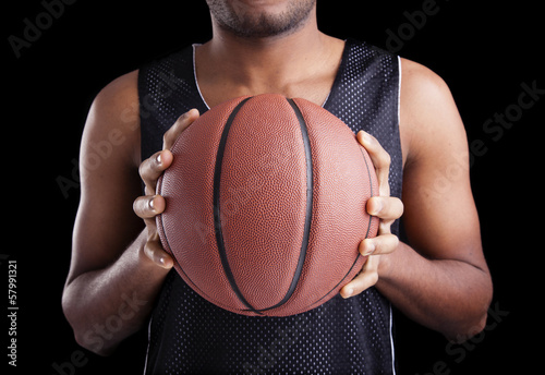 Basketball player holding a ball against dark background © cristovao31