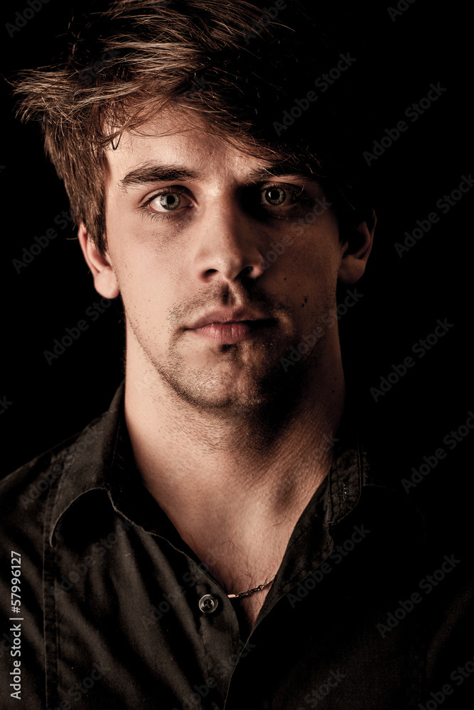 Obraz premium Portrait of pensive young man over black background