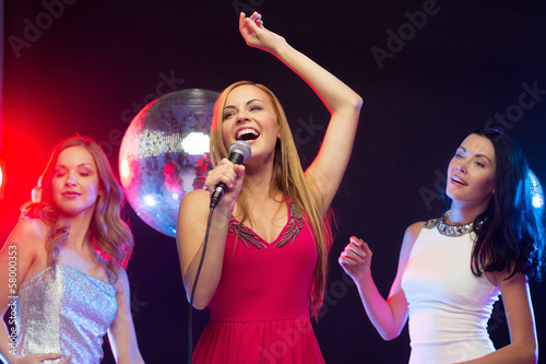three smiling women dancing and singing karaoke