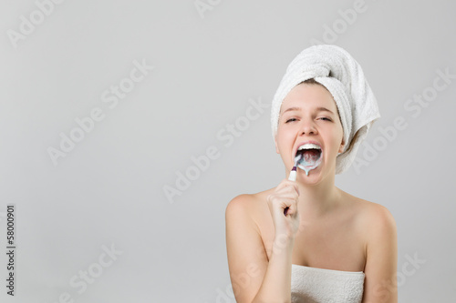 pretty girl brushing her teeth with mouth open