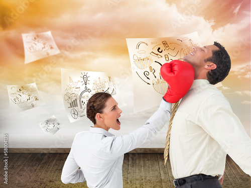 Composite image of businesswoman hitting a businessman with boxi photo