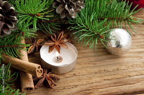 Holiday decoration with candle,fir and cinnamon on wooden backgr