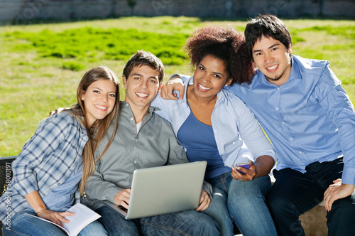 Students With Laptop And Book Sitting In College Campus