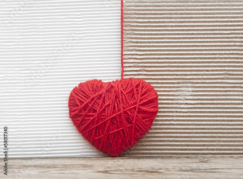 heart made of red yarn hanging on cardboard background