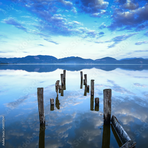 Wooden pier or jetty remains on a lake sunset. Tuscany, Italy