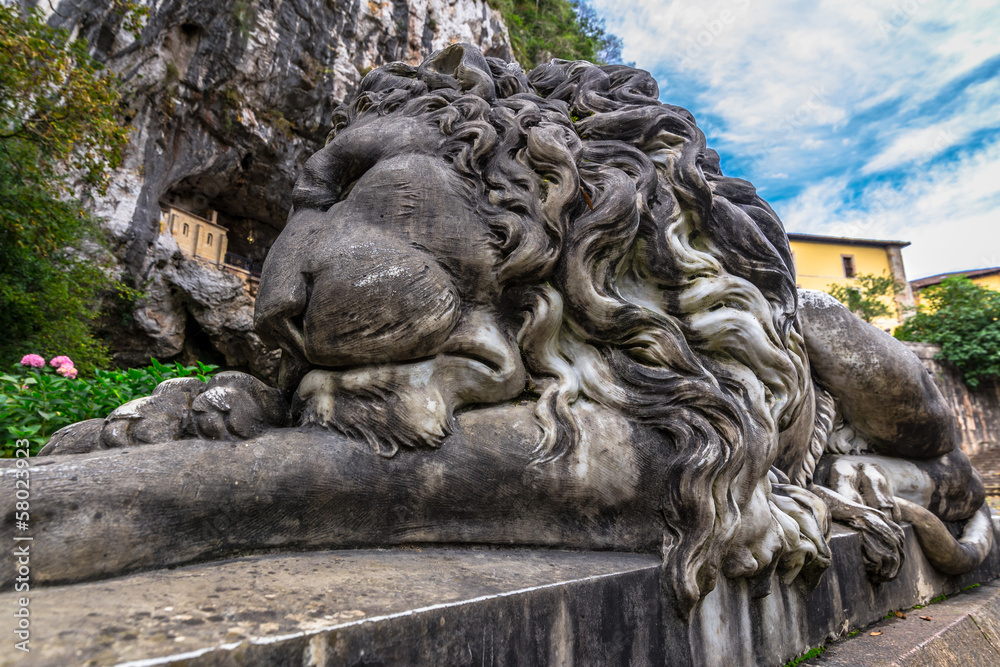 Lion sculpture in Covadonga with the hermitage of the holy cave