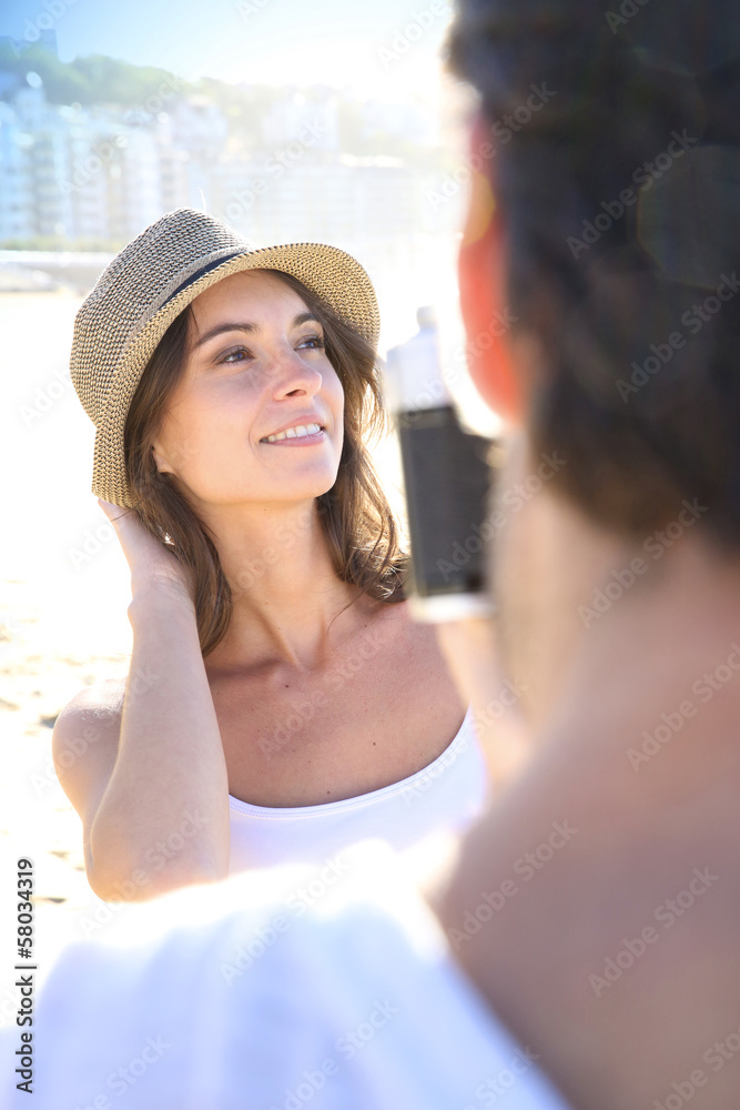 Man taking picture of beautiful woman at the beach