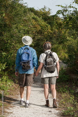 Mature couple holding hands and hiking on nature trail