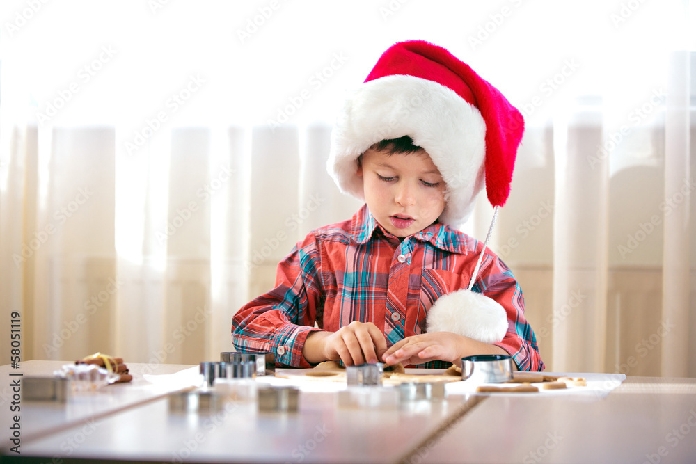 Little boy helping at kitchen with baking cookies