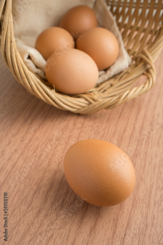 An egg on wooden table and eggs in a wicker basket