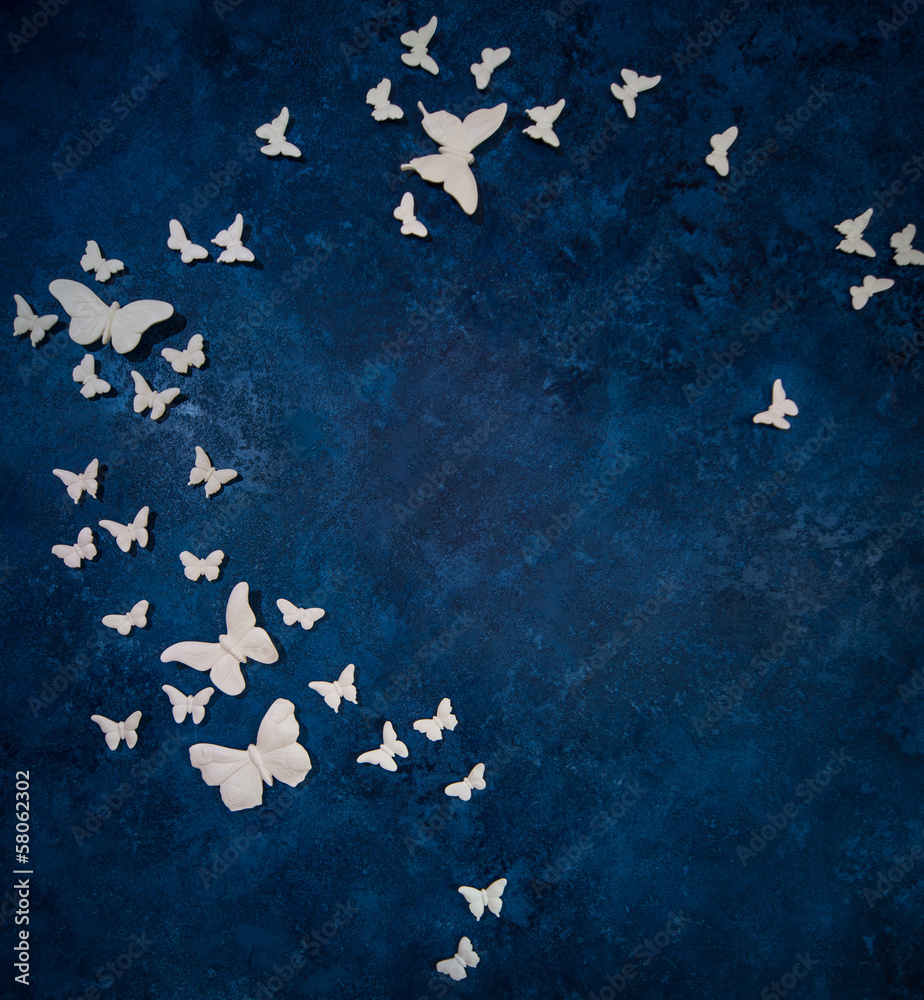 Fototapeta premium White artificial butterflies over dark blue background