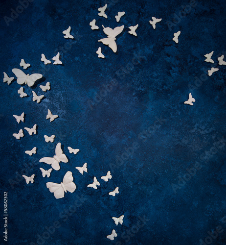 White artificial butterflies over dark blue background