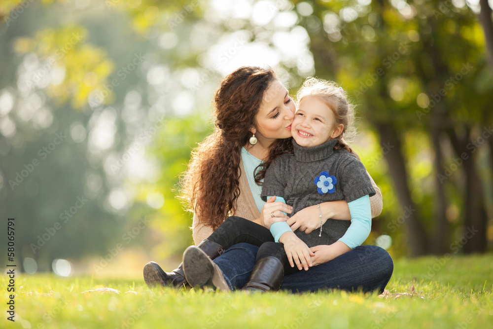 Mother kissing her daughter in the park Mother kissing her daughter in the park
