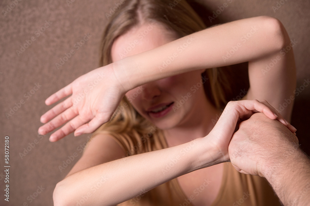 Young woman protecting her face from man strikes Young woman protecting her face from man strikes