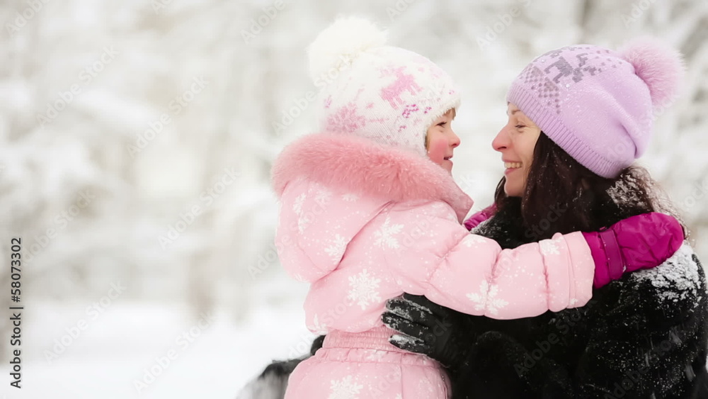 Happy woman and child playing with snow in winter park