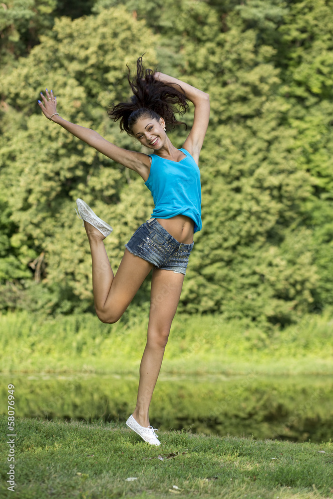 Beautiful girl jumping for joy in a summer park Beautiful girl jumping for joy in a summer park