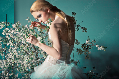 Bride in wedding dress behind bush with flowers