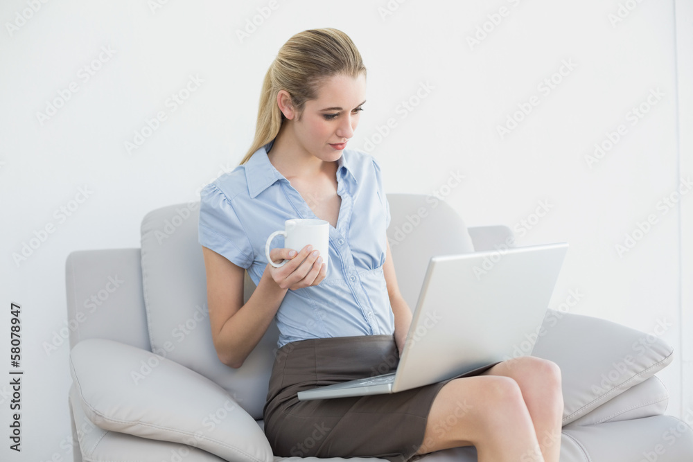 Lovely young businesswoman working on laptop holding a cup Lovely young businesswoman working on laptop holding a cup