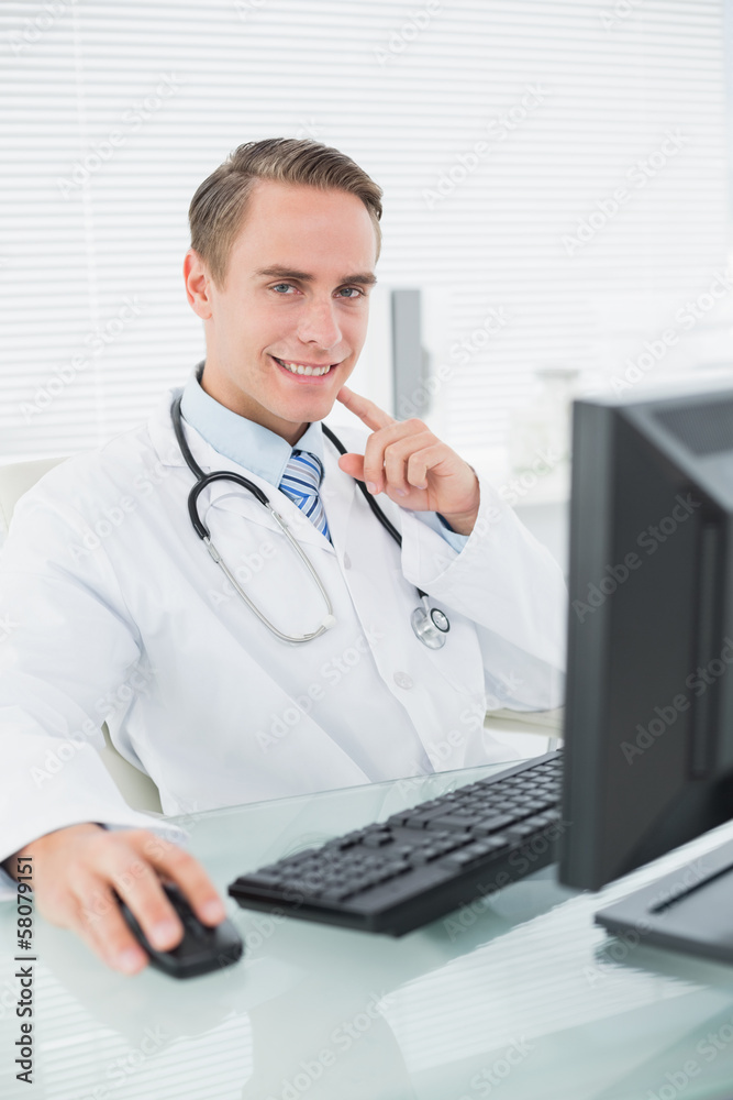 Smiling male doctor with computer at medical office Smiling male doctor with computer at medical office