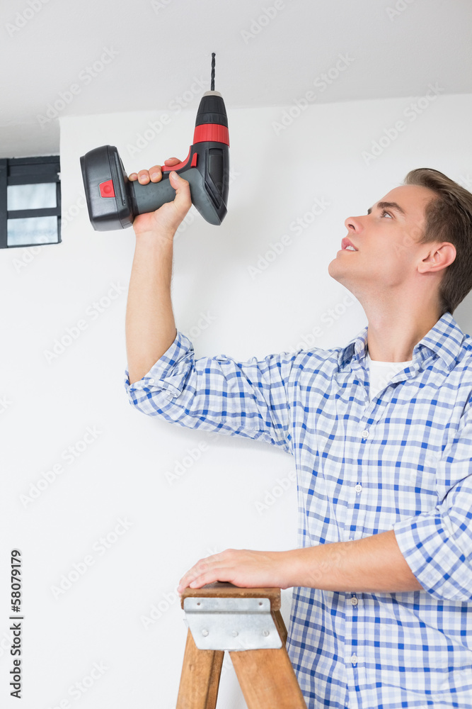 Handyman using a cordless drill to the ceiling Handyman using a cordless drill to the ceiling