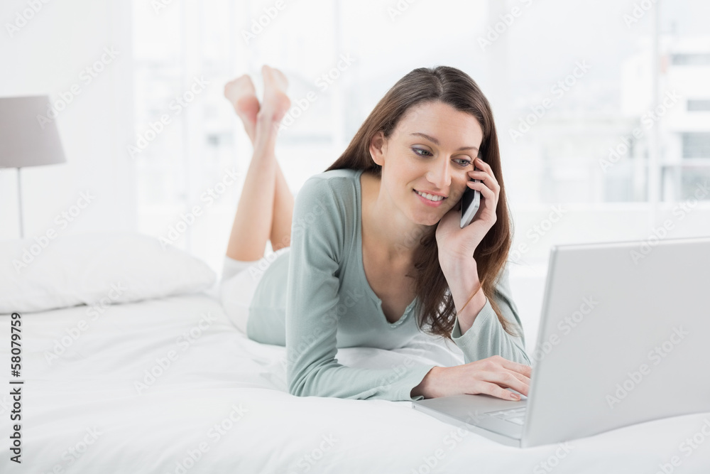 Casual woman using cellphone and laptop in bed Casual woman using cellphone and laptop in bed