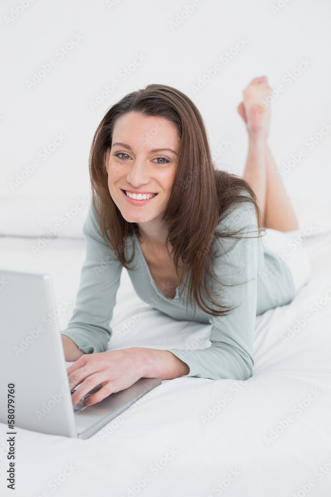 Relaxed casual smiling young woman using laptop in bed Relaxed casual smiling young woman using laptop in bed