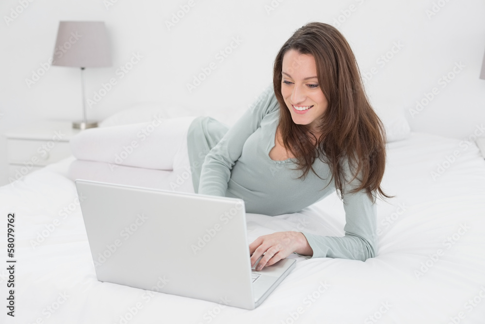 Relaxed casual young woman using laptop in bed Relaxed casual young woman using laptop in bed