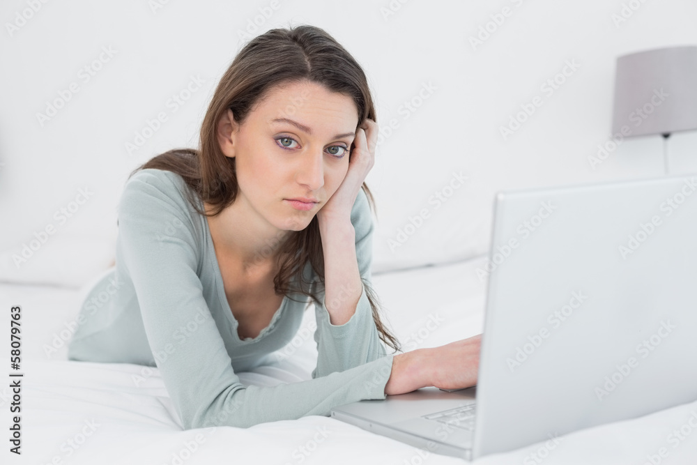 Casual sad young woman using laptop in bed Casual sad young woman using laptop in bed