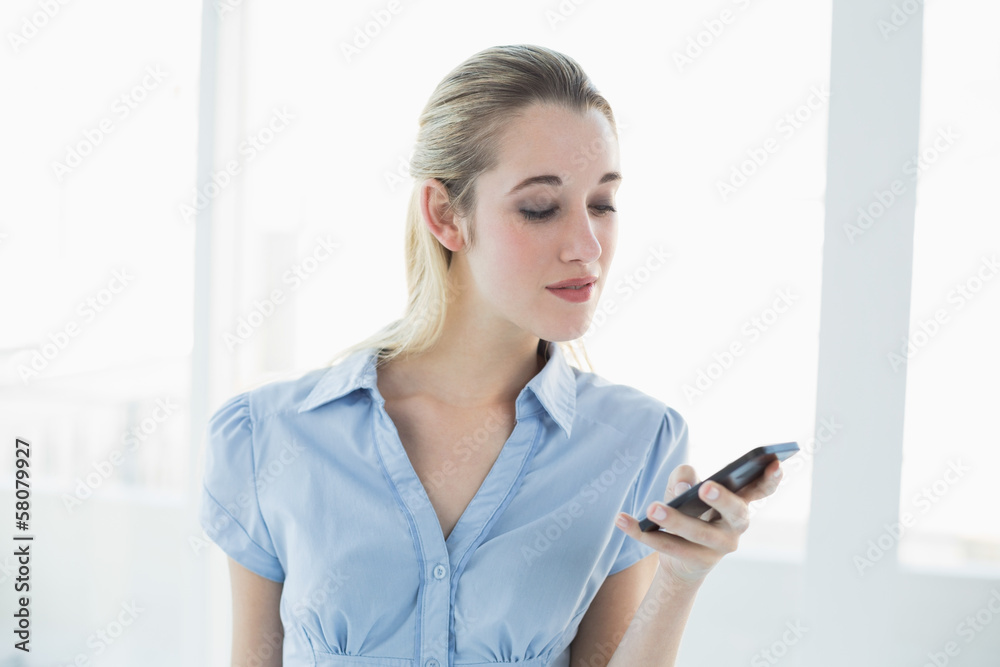 Serious classy businesswoman messaging with her smartphone Serious classy businesswoman messaging with her smartphone
