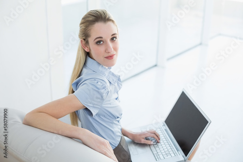Serious classy businesswoman using her notebook sitting on couch