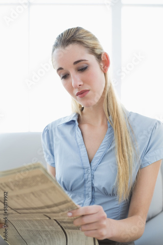 Calm businesswoman reading newspaper while sitting on couch