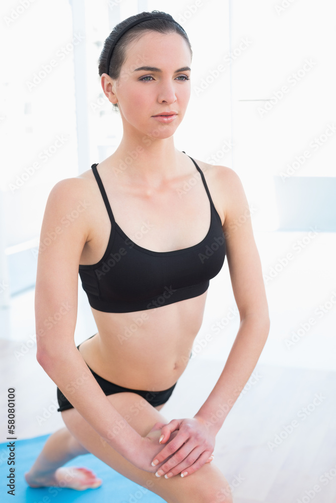 Fit young woman stretching leg in fitness center