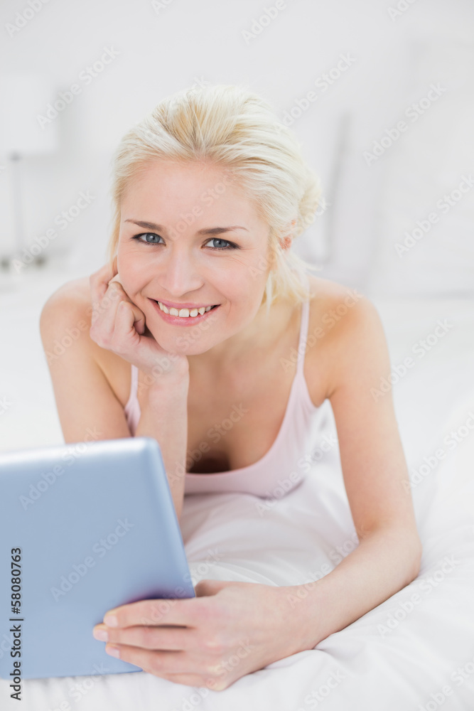Smiling casual young blond with tablet PC in bed Smiling casual young blond with tablet PC in bed