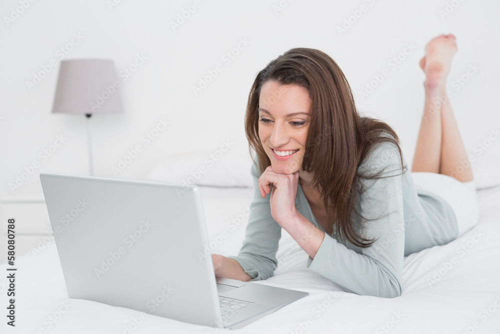 Relaxed casual smiling woman using laptop in bed Relaxed casual smiling woman using laptop in bed