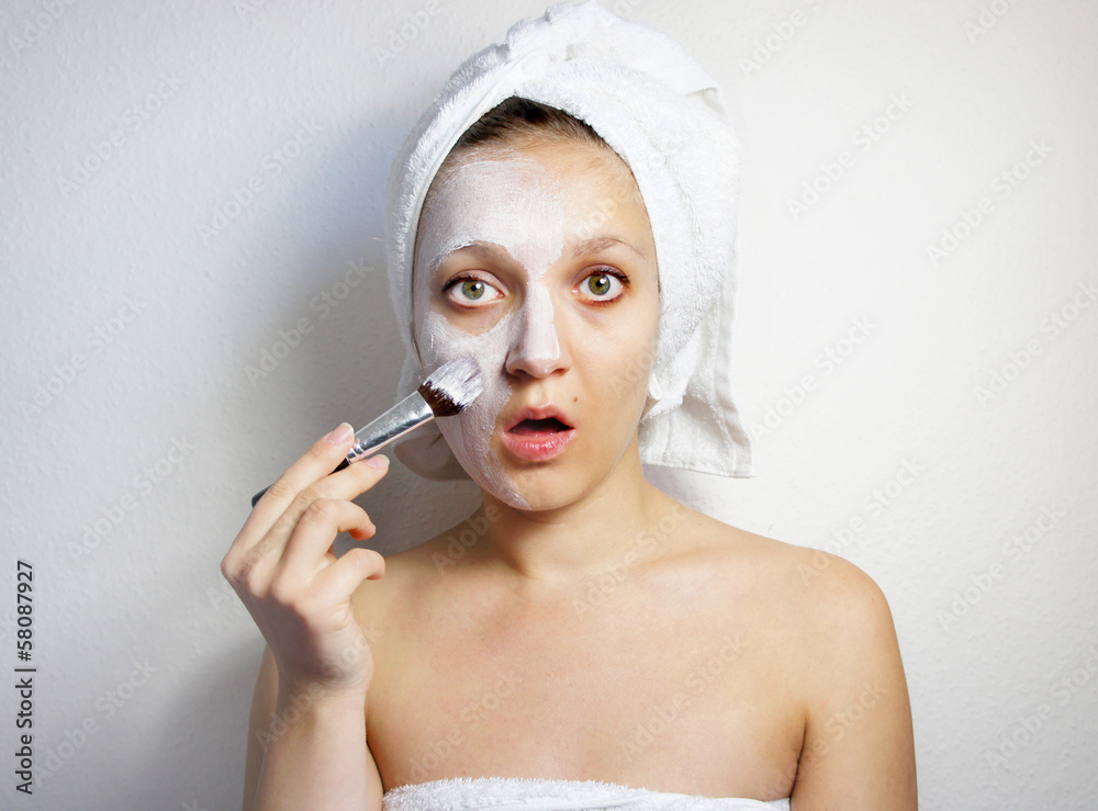 Young beautiful woman with clay facial mask on her face